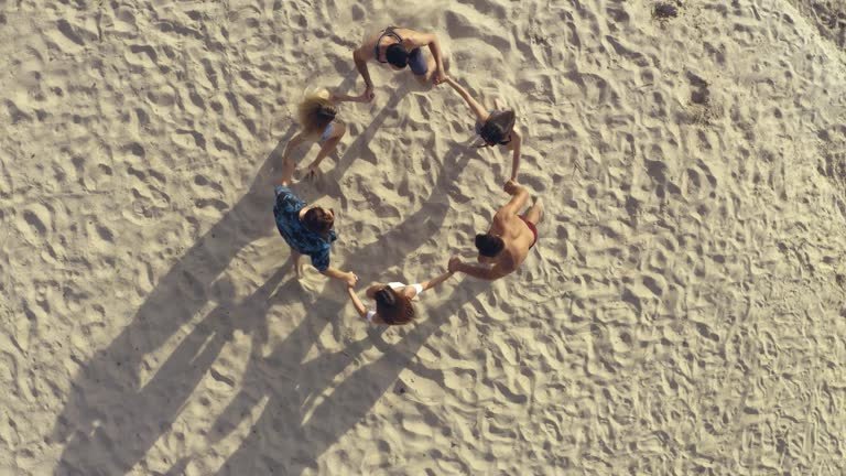 The friends are holding hands and whirling on the beach